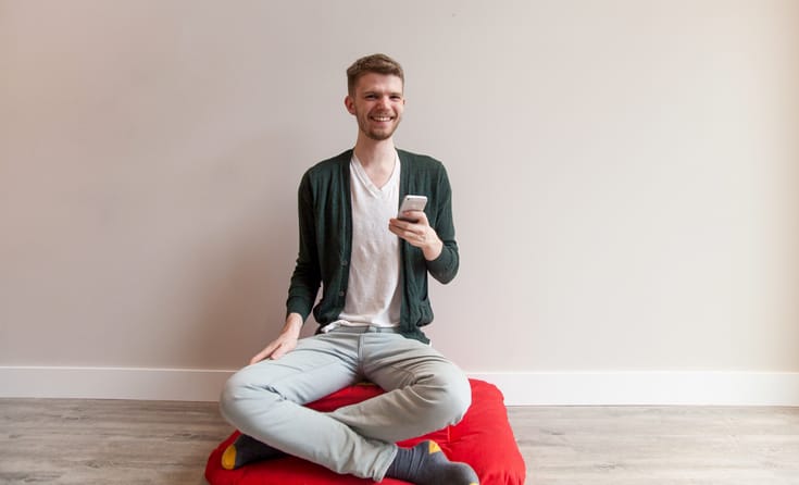 Meditator holding an iPhone.