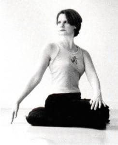 Cyndi Lee sitting with her body twisted in a stretch.