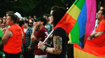 Demonstrator holding a pride flag at a vigil for Orlando.