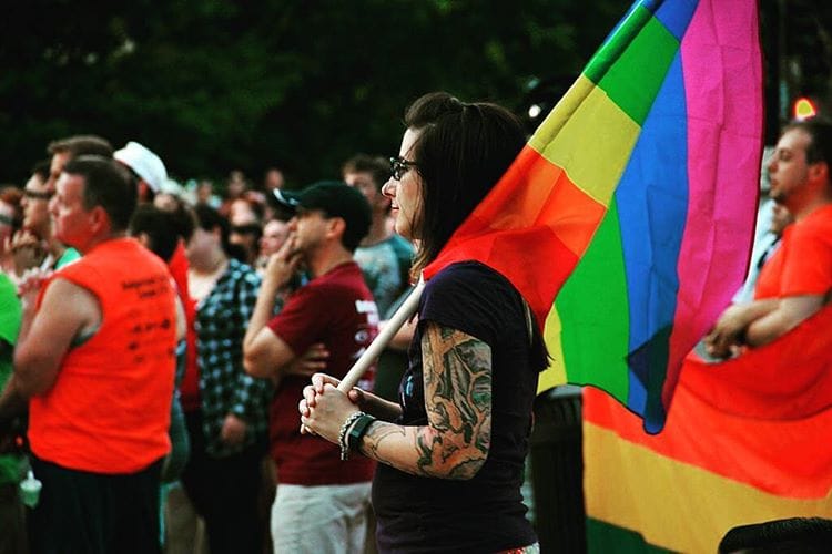 Demonstrator holding a pride flag at a vigil for Orlando.