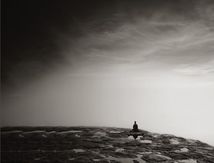 Buddha statue sitting on rocks.