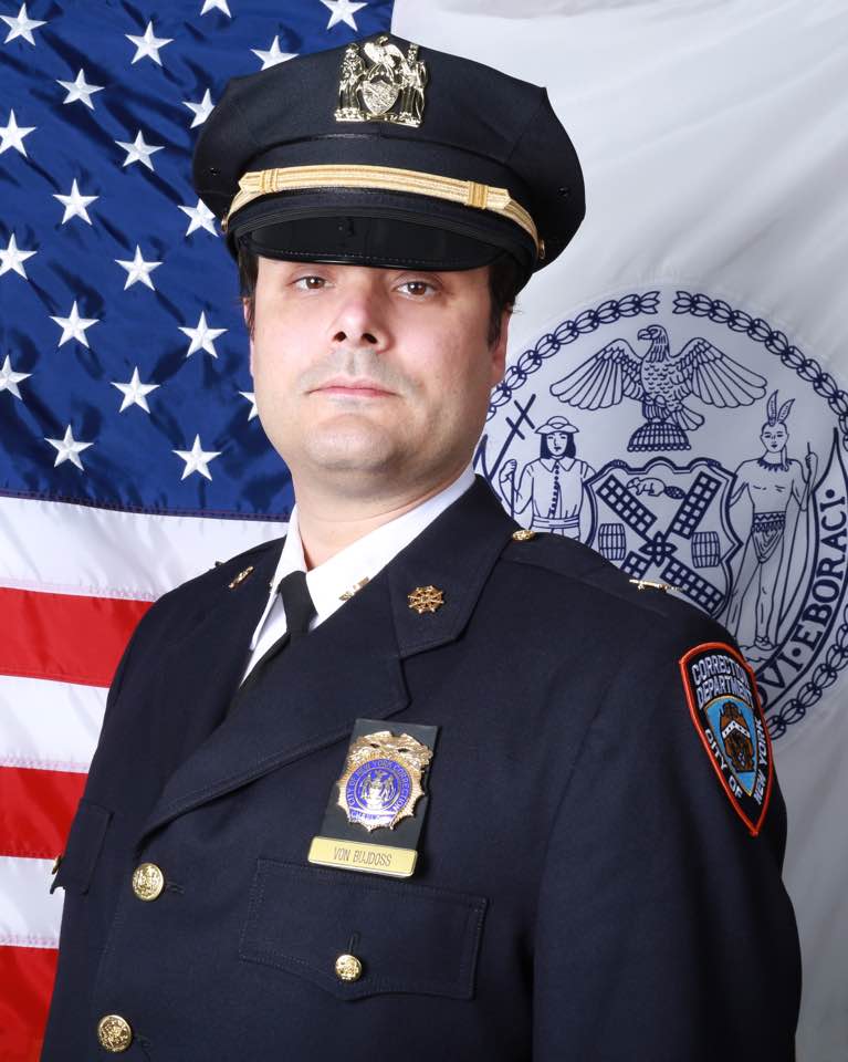 After starting his work at Rikers and receiving his official photo, Justin Von Bujdoss noted: "I have to admit that I struggled with it at first. I've since learned to rejoice in what it means to not take oneself so seriously."