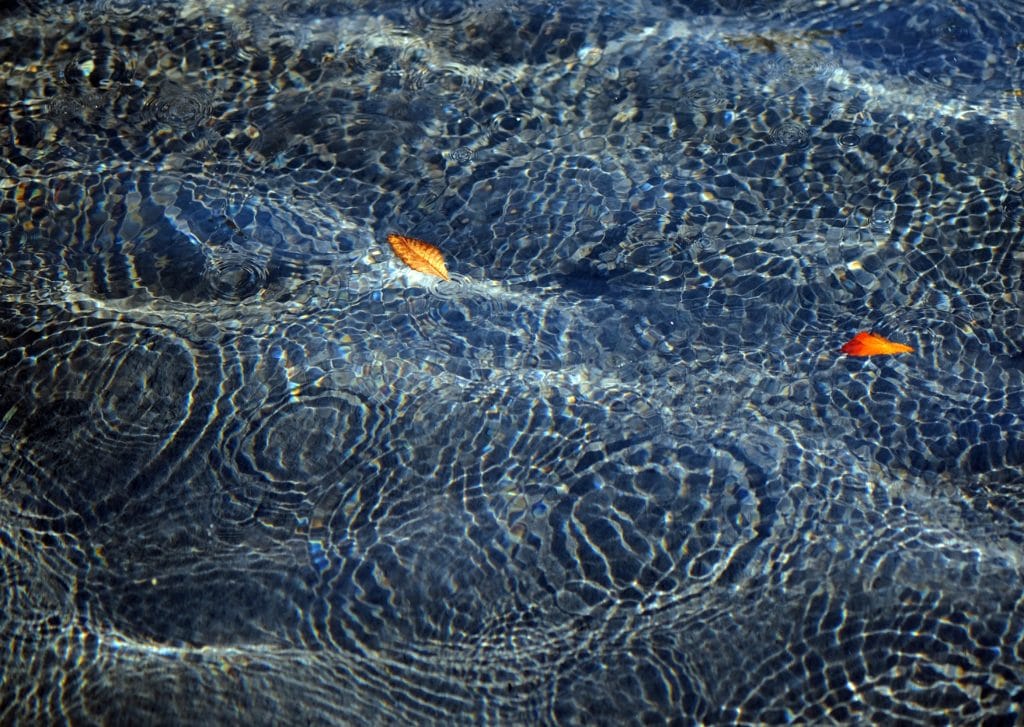 A pool of water with droplets going into the pool.