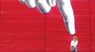 woman in front of pointing graffiti