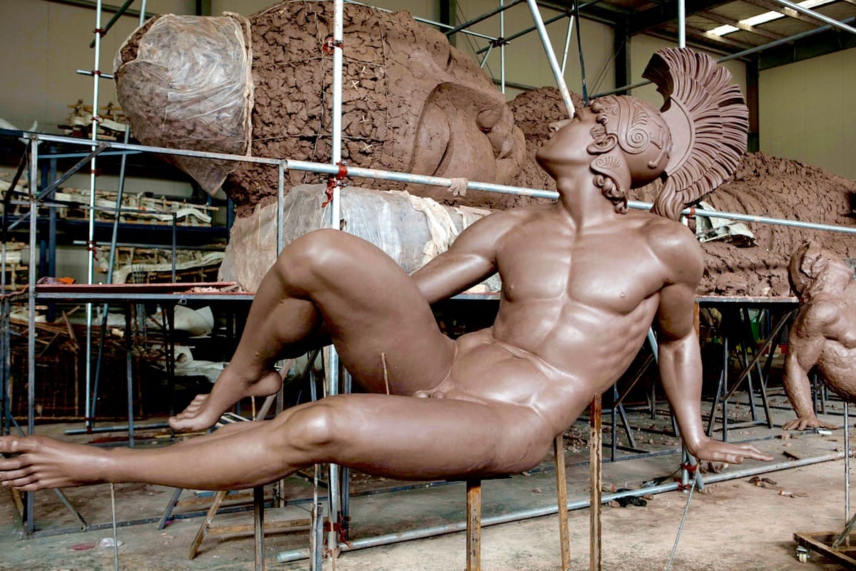 Wounded achilles sculpture next to giant Buddha sleeping.