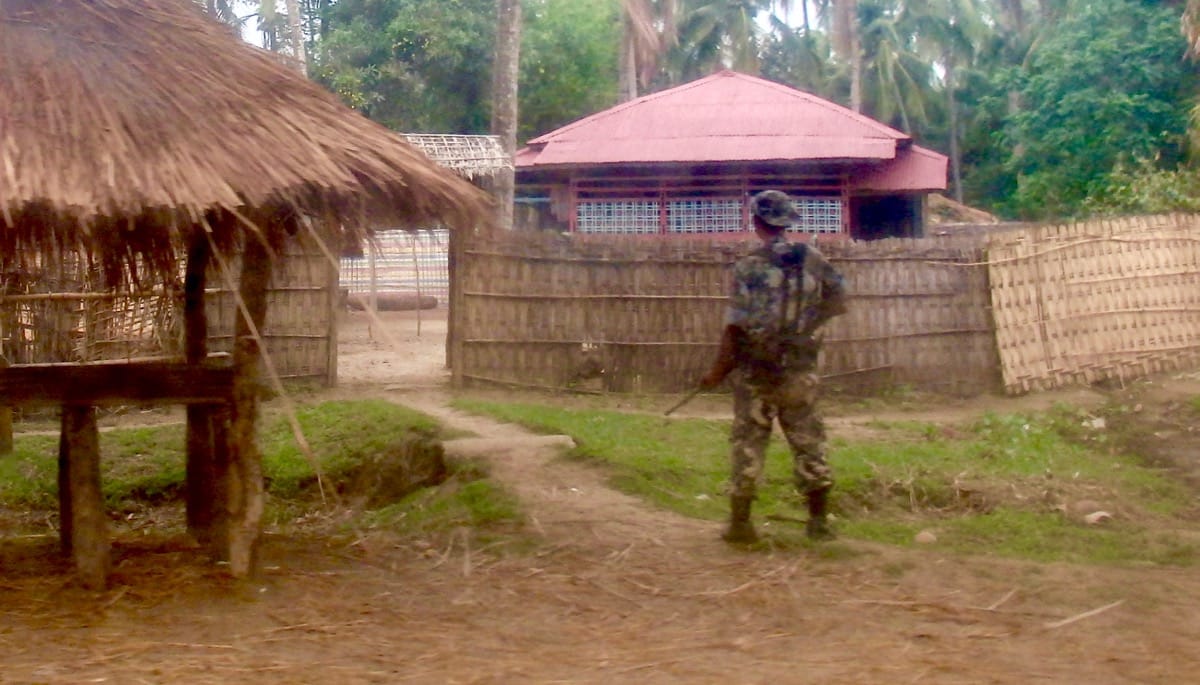 A soldier stands guard at the entrance to a house.