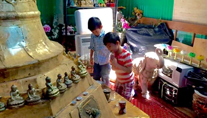 Two boys bowing to a stupa.