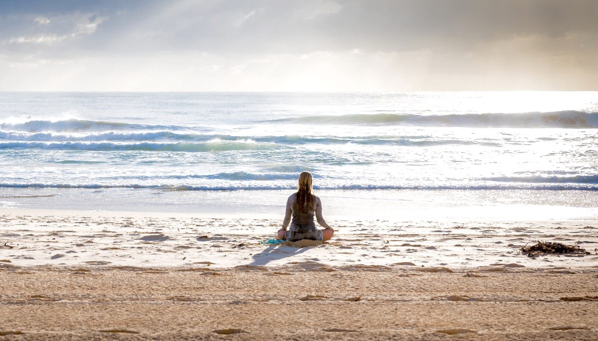 Woman meditating on the beach.
