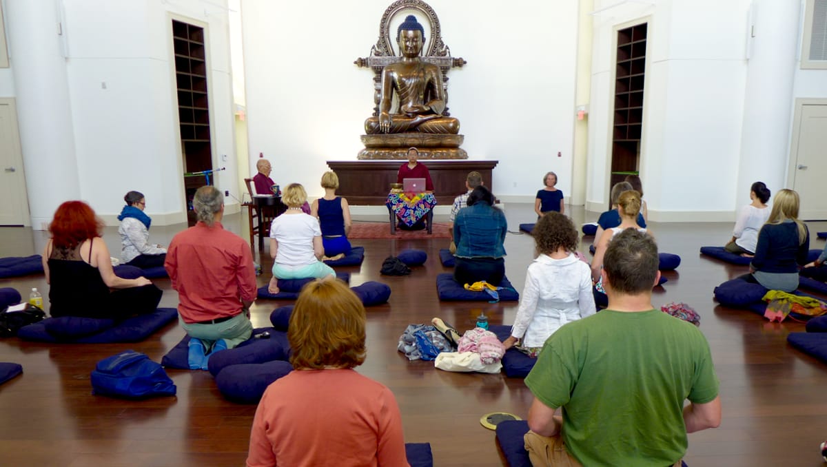Main shrine hall with participants, teacher, and Buddha statue.