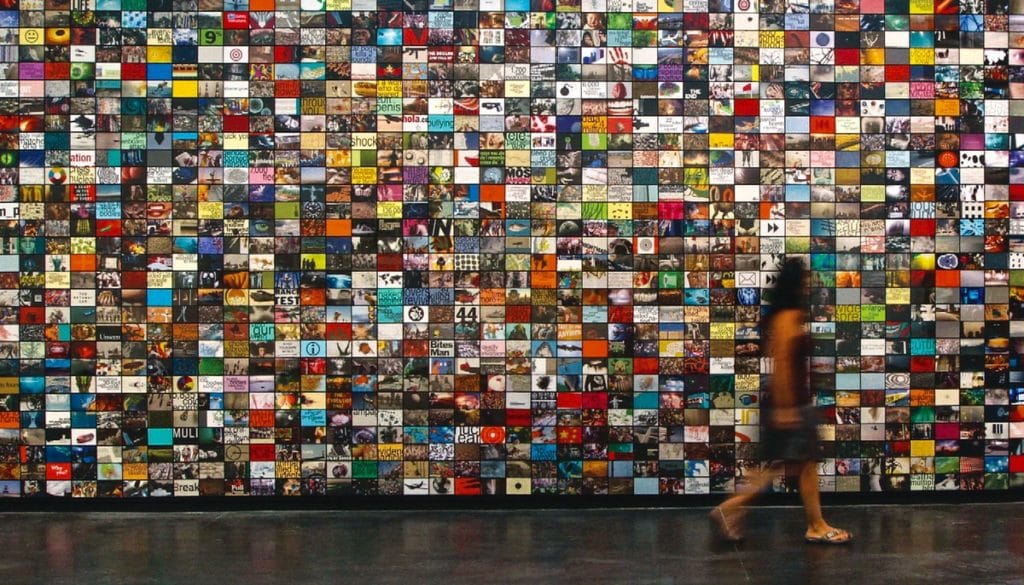A woman walks in front of a wall of screens.
