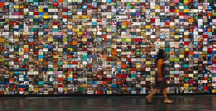 A woman walks in front of a wall of screens.