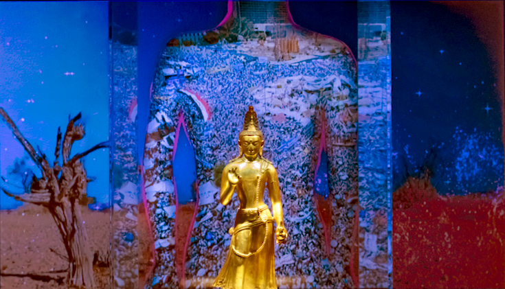 Statue of maitreya in front of a projected animation.