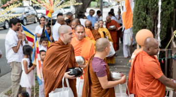 Monks in orange robes walking on alms rounds in Los Angeles.