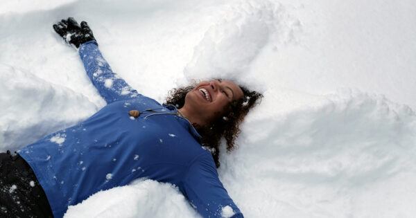 Woman makes a snow angel.