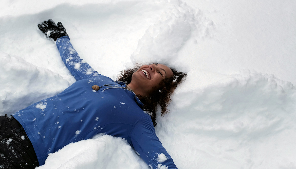 Woman makes a snow angel.