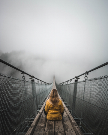 Woman meditating on footbridge in the fod.