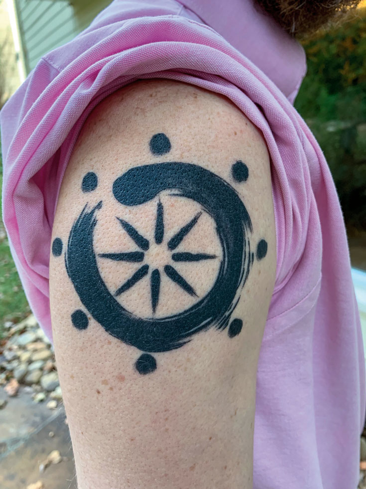 A photo of a tattoo. There is a circle with small circles on the outside.