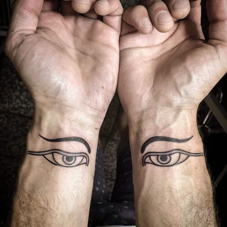 A tattoo on the inside of a person's wrists. Each wrist has a drawing on an eye with an eyebrow above. 