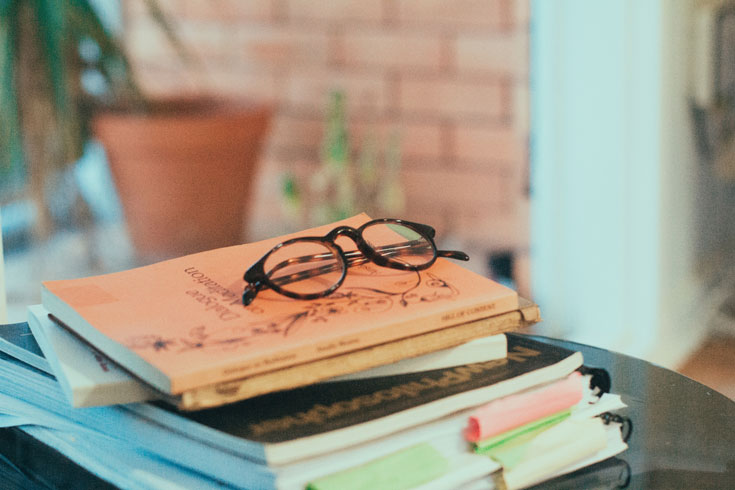 A stack of books with glasses on top of them.