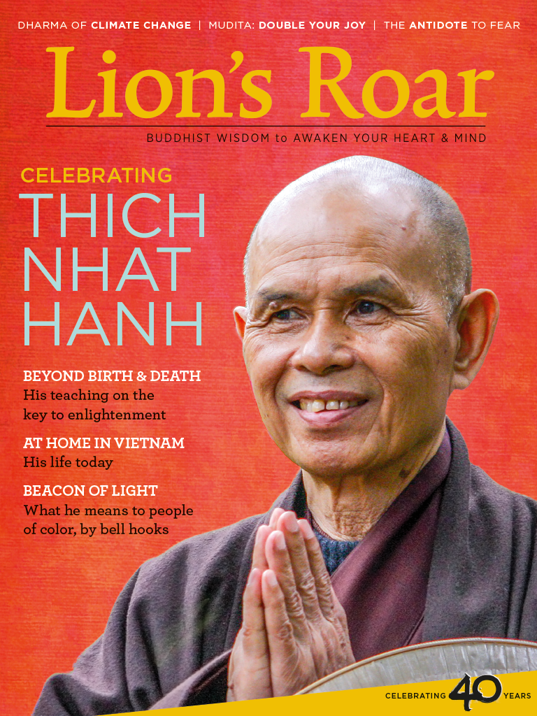 Thich Nhat Hanh on the cover of lion's roar magazine. He is holding his hands together against a red background.