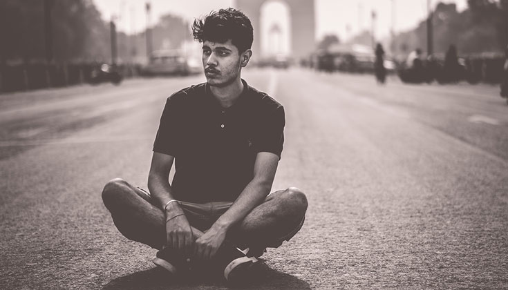 Man sitting cross-legged in the middle of the road.