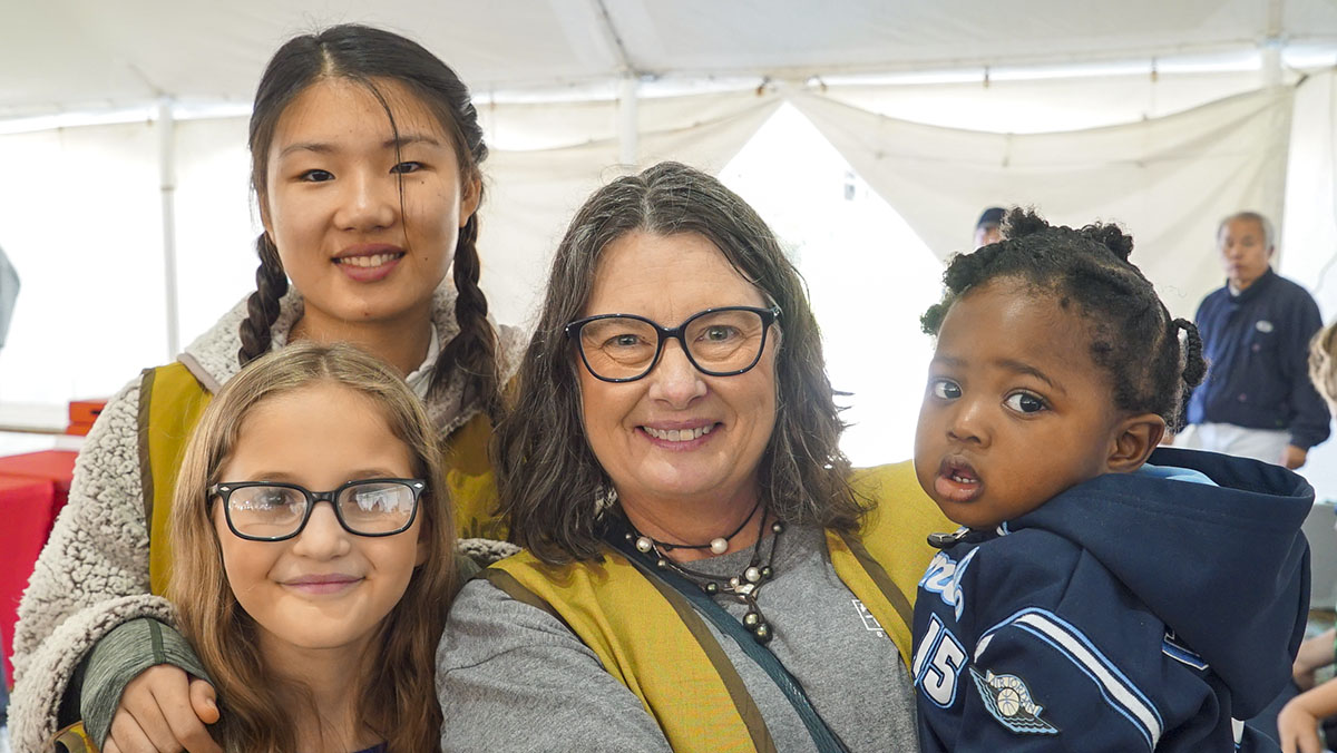 A woman with three young girls next to her. They are all smiling.