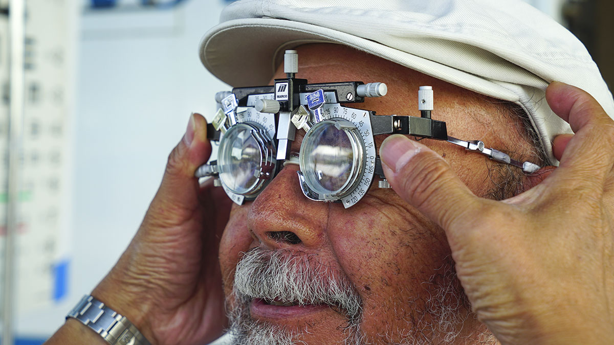 An older man wearing a hat having an eye exam.