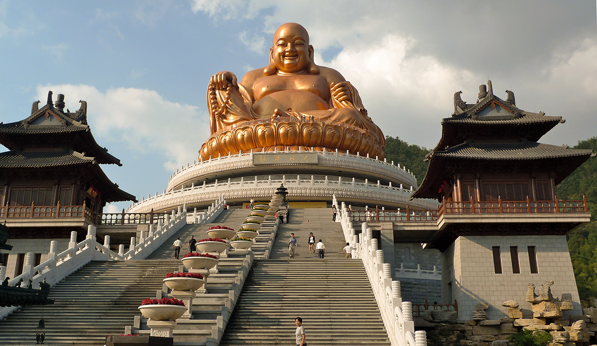Jiuhua Shan in China. A golden statue at the top of a large staircase.