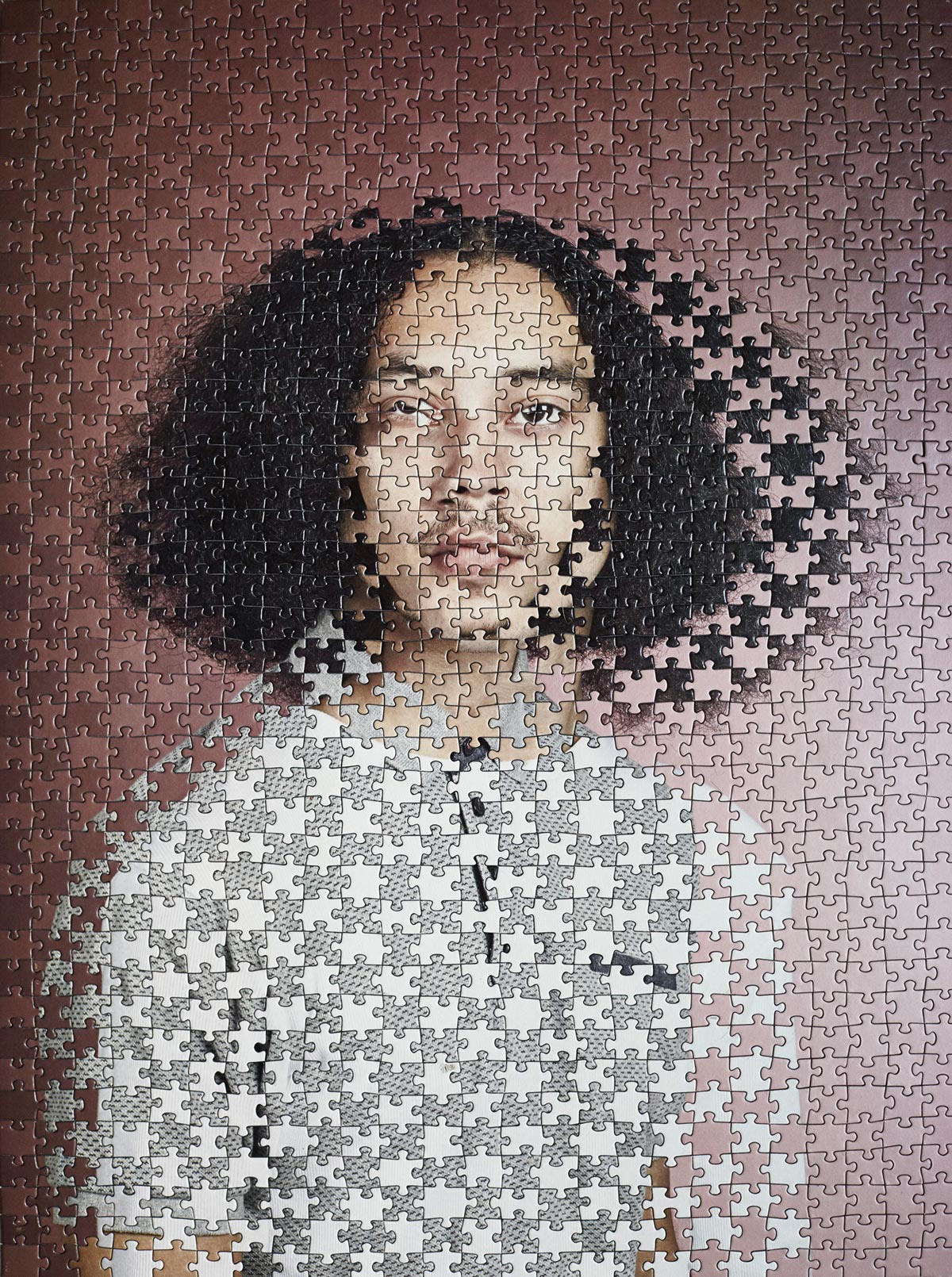 A messed up puzzle that forms a photo of a person with a grey shirt.