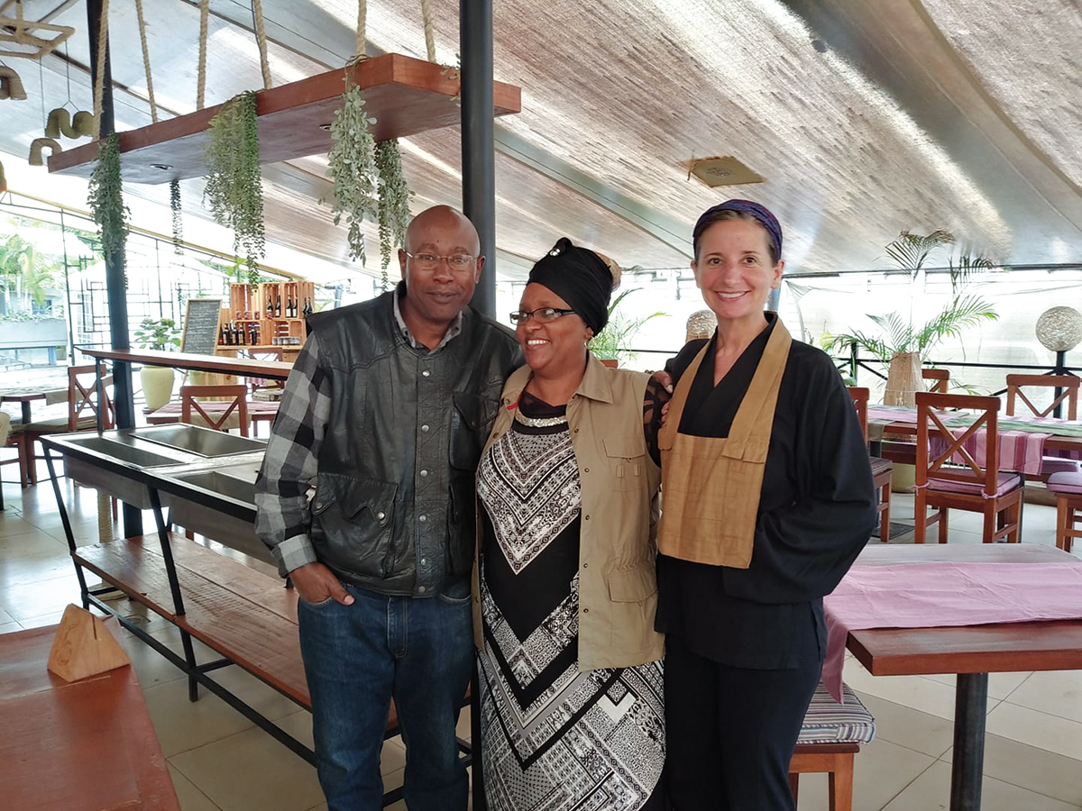 John, Esther, and Joan stand with their arms around eachother in a cafe in Nairobi.