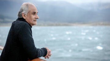 Pico Iyer looks over railing at water.