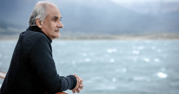 Pico Iyer looks over railing at water.