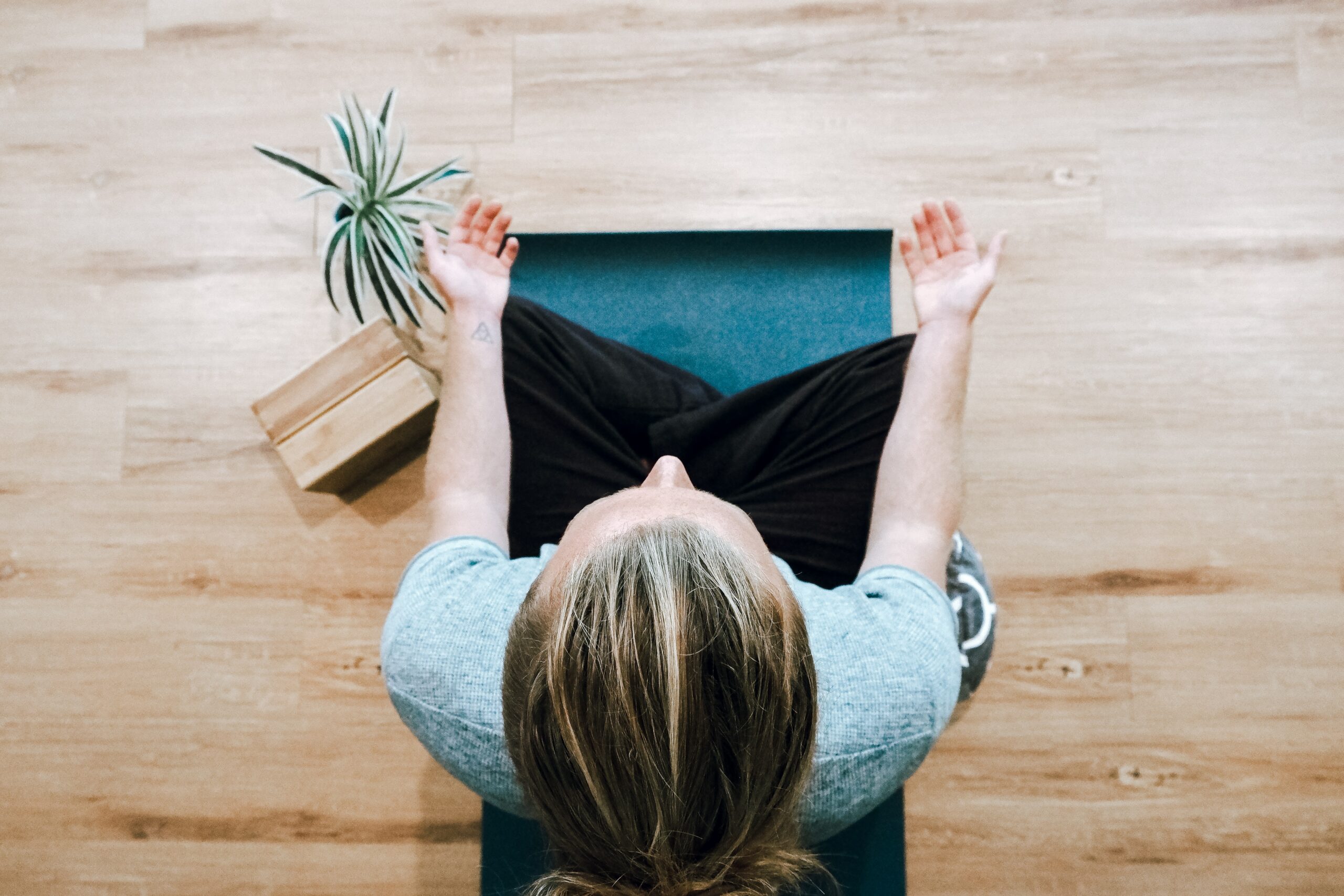 Overhead photo of woman meditating on yoga mat with palms facing up.
